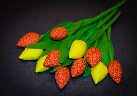 Tulips sewn from yellow and orange fabric lie on gray plain background. Festive decor.の写真素材