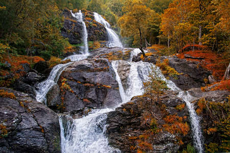 Beautiful waterfalll in autumn forest, Norway. Toned image