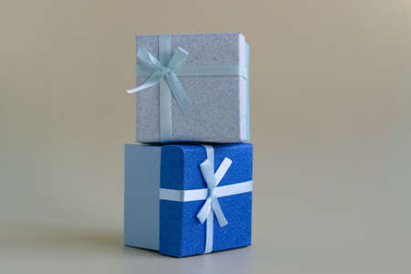 2 gift boxes tied with a soft green ribbon stand on top of each other on a yellow background