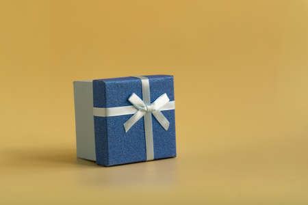 The gift is tied with a soft green ribbon on a yellow backgroundの写真素材