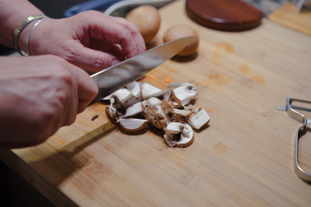 Closeup of hands cutting fresh mushrooms on kitchen board. Cooking healthy food.の写真素材