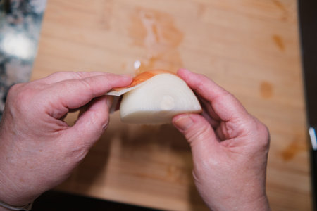 Closeup of hands peeling fresh onion on kitchen board. Cooking healthy food.の写真素材