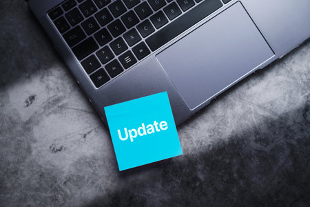 Blue post it on laptop with the word update written on it. Software upgrade concept with empty space...