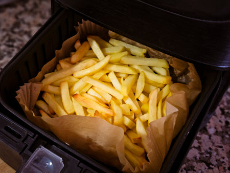Air fryer with homemade grilled potatoes and greaseproof paper.