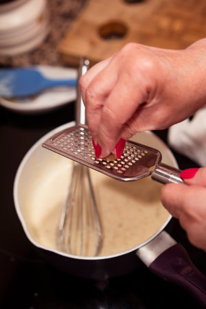 Preparing delicious bechamel sauce in a pan and grating nutmeg.の写真素材