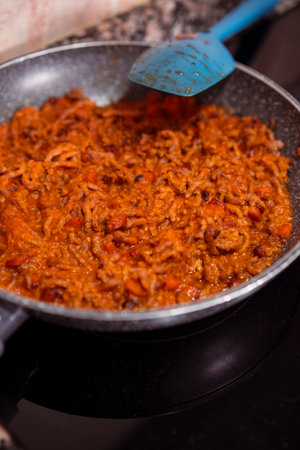 Mince meat with chopped carrots and homemade tomato sauce cooking on frying pan on induction stove. Cooking delicious dish with fresh mince meat.の写真素材
