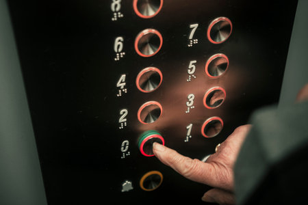 Close up of senior woman hand pressing an elevator button with braille numbers.