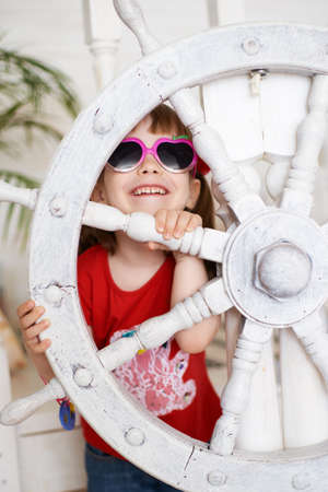 Smiling young girl in sunglasses with steering wheel.の写真素材