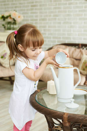 Young smiling cute girl pouring water in jar.の写真素材