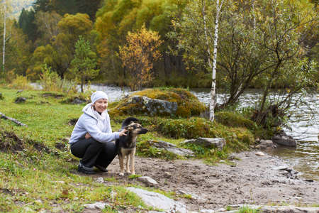 Woman with dog around Altai mountain river.の写真素材