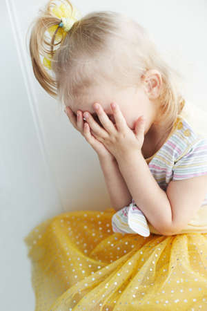 Weeping young blond girl indoor.の写真素材