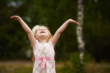 Young girl hands up. Happy. Outdoors.の写真素材