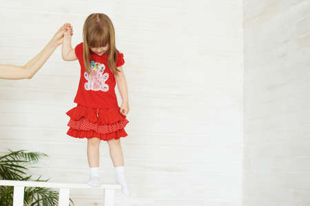 Young cute girl in red standing on railing.の写真素材