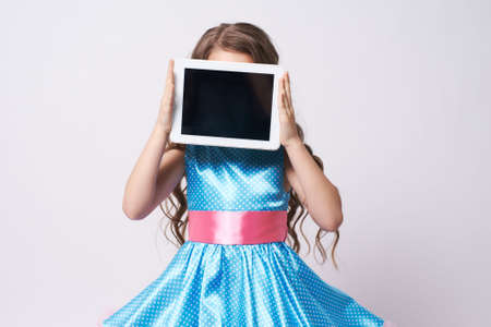 Girl. Tablet. Portrait child. Dress. Blue. Technologies.の写真素材