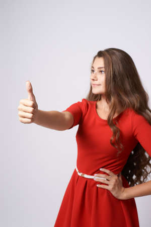 Gesture approval. Portrait girl. Red dress. Brunette.の写真素材