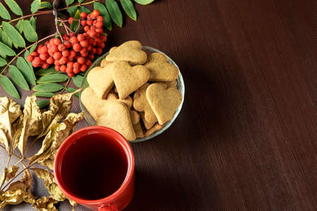 Autumn still life. Heart cookie. Black tea. Yellow leaves. Rowan branchの写真素材