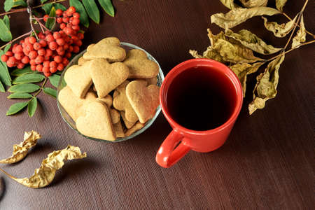 Autumn still life. Heart cookie. Black tea. Rowan branch. Yellow leaves.の写真素材