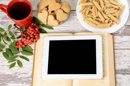 Work on tablet. Old book. Ginger cookies hearts.の写真素材
