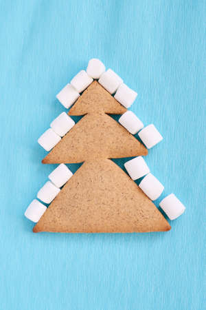 Christmas tree biscuits. Blue background. White small marshmallow.の写真素材