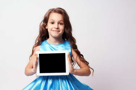 Beautiful little girl. Modern technologies. Lush blue dress.の写真素材
