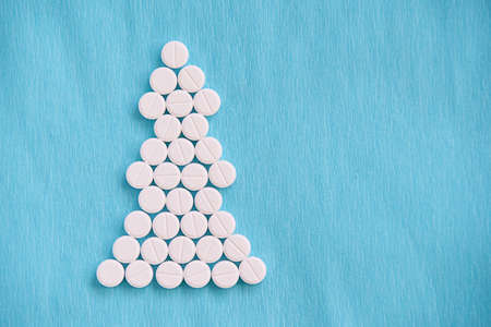 Round white tablets. Interesting Christmas tree. Blue background.の写真素材
