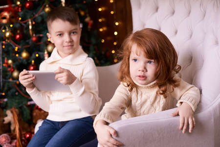 Boy and girl. Christmas interior. Computer tablet.の写真素材