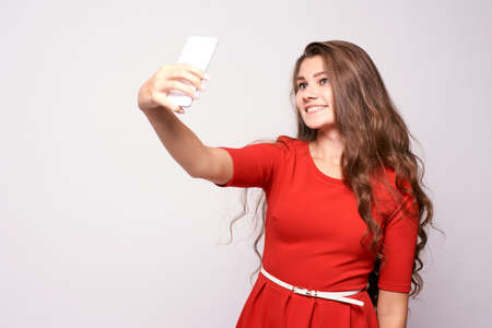 Portrait girl. Selfie on phone. Red dress.の写真素材