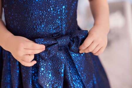 Blue dress. Great bow. Childrens hands. Horizontally.の写真素材
