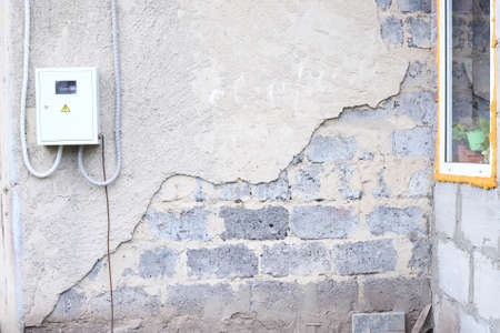 Destroyed wall. Gray plaster. Large uneven stones.