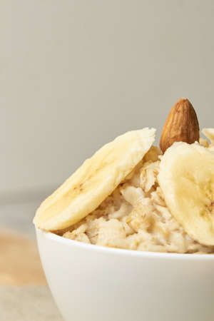 White bowl. Oatmeal with almonds and banana. Neutral background.の写真素材