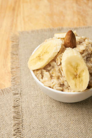 Oatmeal with almonds and banana. White bowl. Neutral background.の写真素材