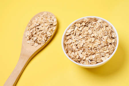 Oat flakes. Healthy eating. Wooden spoon. Yellow background.の写真素材