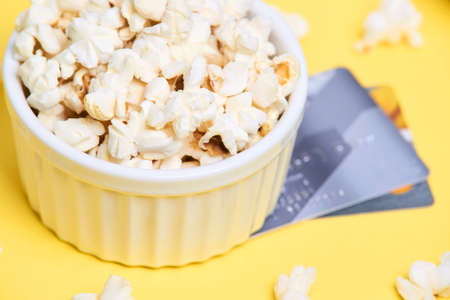 Fresh white popcorn. Yellow background. White plate.の写真素材