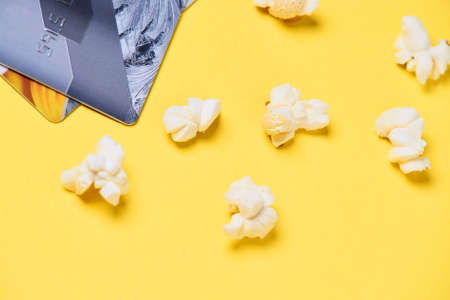 Fresh white popcorn. Plastic card. Yellow background.