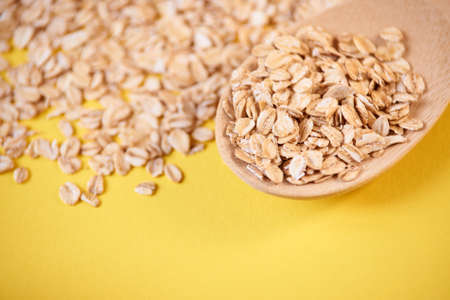 Yellow bright bacground. Wooden spoon. Healthy breakfast with oatmeal.の写真素材