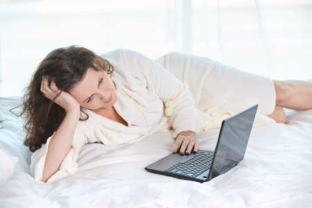 Beautiful girl. Work at home. Black notebook. White background.の写真素材