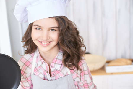 Beautiful girl. Little cook. White cap. Brown curly hair.の写真素材
