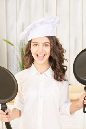 Young female chef with two pancake pans.の写真素材