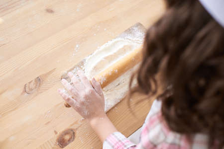 Preparation of the test. Small hands. Wooden table. White flour.