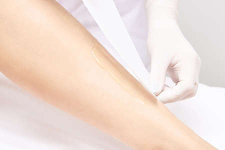 Waxing woman leg. Sugar hair removal. laser service epilation. Salon wax beautician procedure.の写真素材