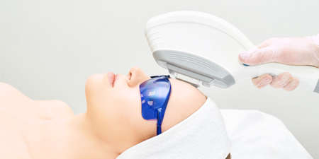 IPL laser clinic treatment. Cosmetology medical procedure. Face skin ejuvenation. Beautician device. Anti acne. Young beautiful girl. Woman facial care.の写真素材