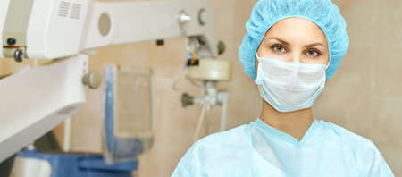 Pretty doctor woman portrait. Ophthalmology laser microscope operation. Clinic room. Patient eye...