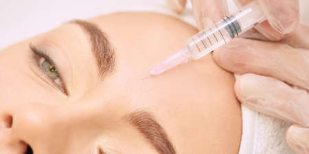 Forehead woman surgery. Anti wrinkle filler. Cosmetology injection. Face skin rejuvenation. Doctor injecting collagen acid.の写真素材