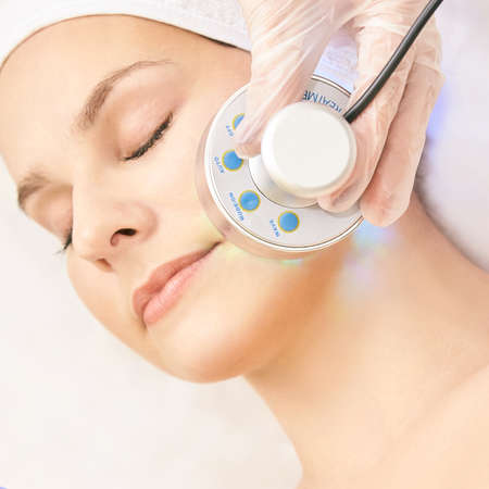 Light infrared therapy. Cosmetology head procedure. Beauty woman face. Cosmetic salon device. Facial skin rejuvenation.の写真素材