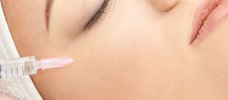 Woman face cosmetology treatment. Biorevitalization skin therapy. Doctor insert filler. Girl clinic facial mesotherapy. Injecting in medical salon.の写真素材
