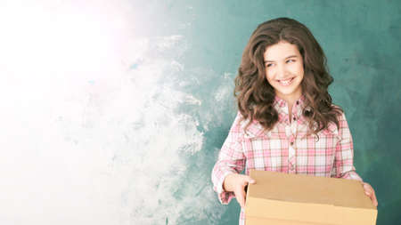 Young girl with delivery box. Happy child relocation stuff. Holding mail gift.の写真素材
