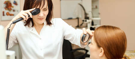 ophthalmologist doctor in exam optician laboratory with female patient. Eye care medical diagnostic. Eyelid treatmentの写真素材