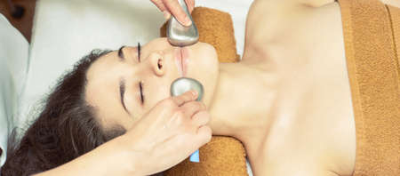 facial ice stick massage. Hot face masseur. Girl at salon with doctor hands.の写真素材