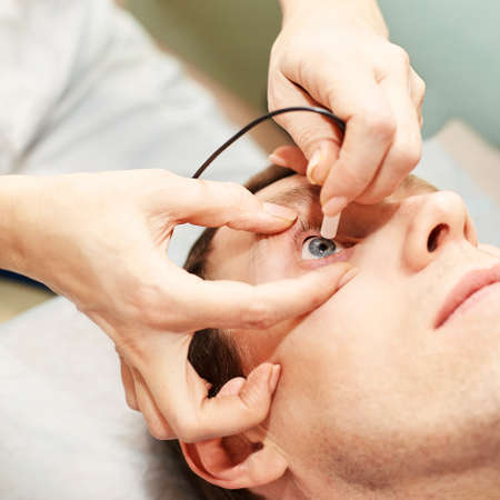 ophthalmologist doctor in exam optician laboratory with male patient. Men eye care medical diagnostic. Eyelid treatment.の写真素材