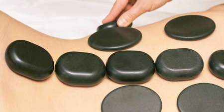 body stone massage. Hot rock masseur. Girl at salon with doctor hands. Relax spa resort.
